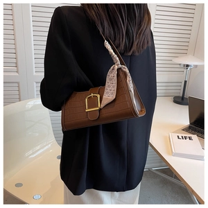 Close-up of brown croc-effect baguette bag with golden buckle and stylish silk scarf detail