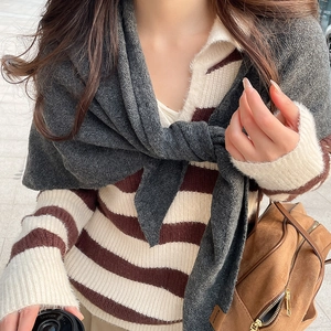 Détail de la texture en maille d'une écharpe grise et d'un pull d'hiver à rayures chic