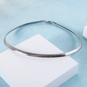 Detailed view of silver flat snake chain necklace on minimalist white block display