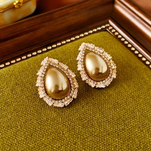 Vue macro des boucles d'oreilles vintage en or avec perle centrale et halo de strass