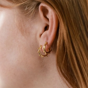Close-up of elegant gold beaded hoop earrings worn by a woman for a stylish look