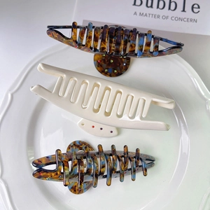 Detailed set of three colorful acetate hair claws with sparkling rhinestones on a ceramic tray