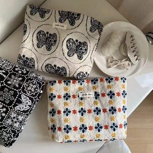 Flat lay of embroidered canvas makeup bags with floral patterns and woven labels