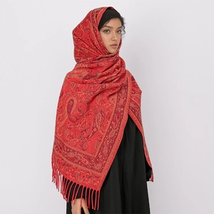 Detail of red paisley scarf with tassels worn as a headscarf on studio background