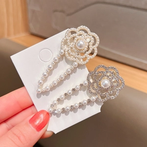 Detail showing artificial pearl flower hair clips with sparkling rhinestones in gold