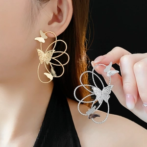 Detailed view of hollow butterfly earrings in gold and silver finish on model