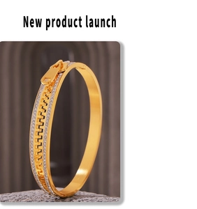 Detailed shot of gold-plated zipper bangle with sparkling rhinestones on stone base