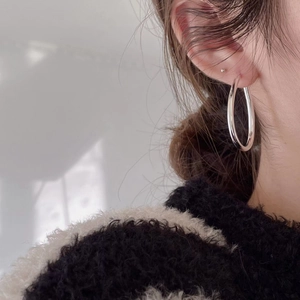 Close-up of a model wearing a large minimalist 925 sterling silver wavy hoop earring
