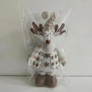 Detail of Christmas reindeer plush toy in knitted outfit inside clear protective packaging