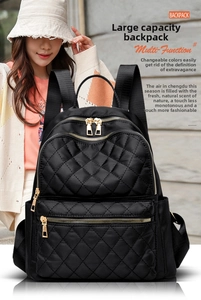 Detail of black quilted nylon backpack with gold zippers shown on a person