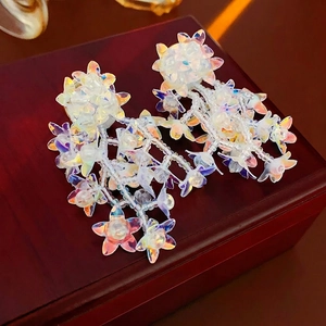 Elegant iridescent flower tassel earrings with mother-of-pearl effect on a jewelry box