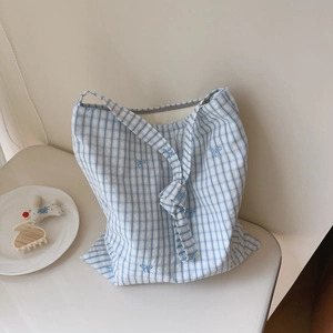 Detailed view of blue plaid cotton tote bag featuring small embroidered bow details
