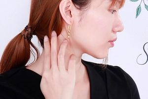Detail view of golden dangle earrings with rectangular links on a female model