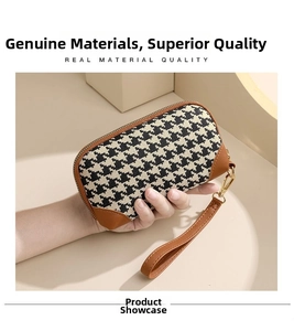 Close-up of houndstooth clutch bag with brown leather trim and metal zipper handle