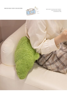 Detail of soft green croissant plush pillow on sofa with cozy teddy velvet texture