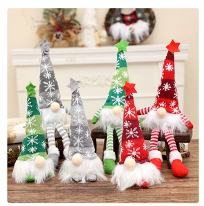 Close-up of glowing Christmas gnomes with knitted star hats on a wooden surface