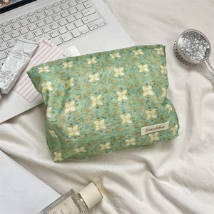 Detailed top view of a green floral cosmetic bag with laptop and toiletries
