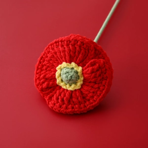 Macro shot of handcrafted crochet red poppy flower with detailed yarn texture and stem