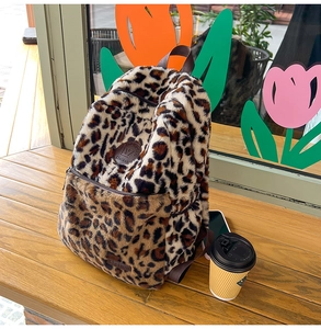 Dettaglio ravvicinato di uno zaino in peluche leopardato su panca con decoro di tulipani