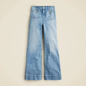 Detail view of high-waisted wide-leg denim jeans with front patch pockets and metal buttons