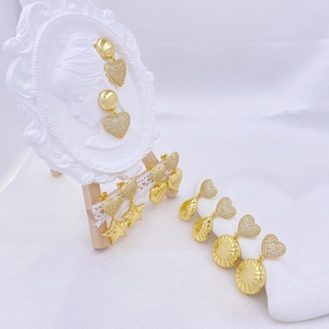 Golden geometric earrings set with star and heart charms on a white display