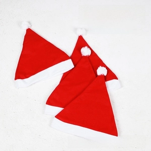 Flat lay of four classic red and white non-woven Christmas hats with soft pom poms