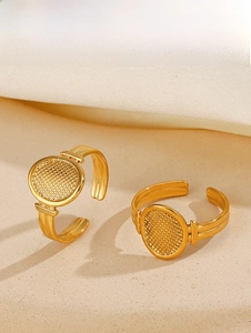 Detailed view of two gold oval textured rings with adjustable bands on a beige surface