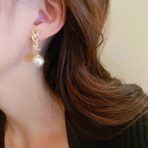 Boucles d'oreilles perles dorées avec lettre et cristaux portées par un mannequin