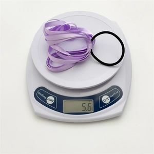 Close-up of lightweight purple satin ribbon hair tie on digital scale weighing 5.6g