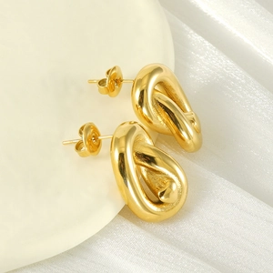 Close-up of golden twist knot stud earrings with polished mirror finish and butterfly backs