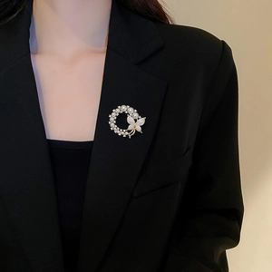 Détail d'une broche fleur papillon avec perles et cristaux sur une veste de tailleur noire