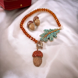 Detail of vintage necklace set with amber beads, crystal pinecone and leaf pendants