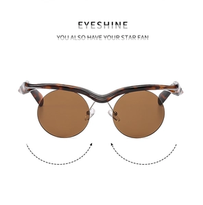 Detail of tortoise shell wavy frame sunglasses with round brown lenses and metal accents