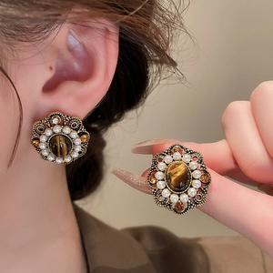 Detail of vintage palace style earrings with brown tiger eye stone and small white pearls