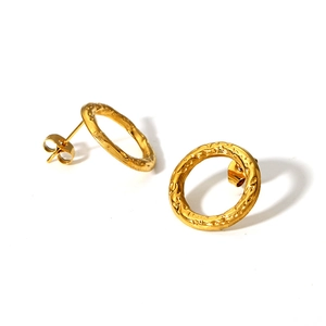 Macro shot of gold-plated hoop earrings with a vintage hammered metal texture finish