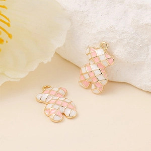 Vue macro de breloques en émail en forme d'ours avec motifs à carreaux rose et blanc