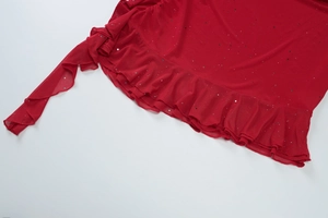 Detailed view of red mesh fabric with shimmering sequins and delicate ruffle hem edges