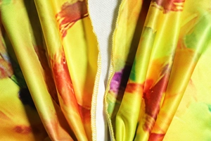 Macro shot of yellow floral dress fabric showing high-quality stitching and silky texture