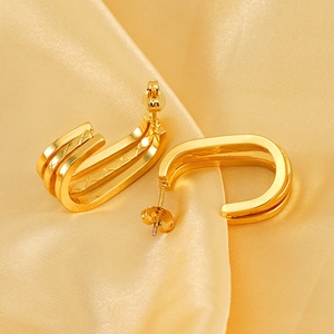 Minimalist gold tiered U-shaped earrings on satin background with luxe metal texture