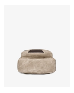 Detail view of beige canvas texture and dark brown leather patch on the crossbody bag