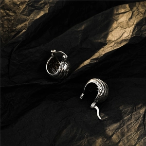 Macro detail of retro silver lava texture on metallic earrings with low-key lighting