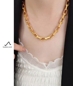 Close-up of golden stainless steel chunky curb chain necklace worn by a model