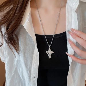 Macro detail of silver cross pendant with sparkling crystals on a delicate chain