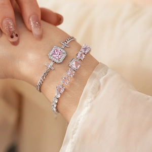 Close-up of sparkling pink zircon square tennis bracelet and chain bracelet on wrist