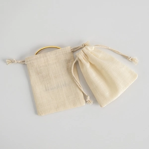 Close-up of beige cotton linen drawstring bags showing natural texture for jewelry storage