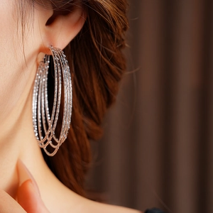 Close-up of textured multi-layered silver hoop earrings worn by a model in detail
