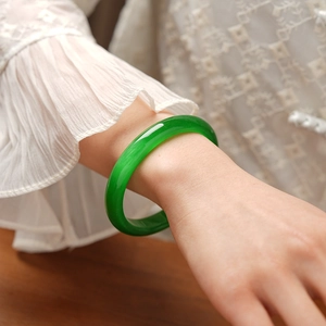 Close-up of a vibrant green cat eye stone bangle with a polished round finish on a wrist