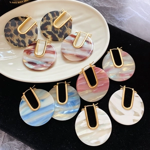 Détail de boucles d'oreilles U plaquées or 18k avec pendentifs ronds en résine marbrée