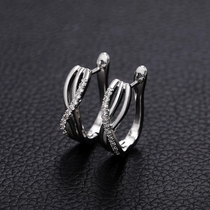 Macro shot of silver crisscross hoop earrings with sparkling cubic zirconia on black leather