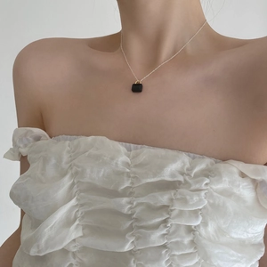 Minimalist silver chain necklace with black zircon lock pendant worn on the collarbone